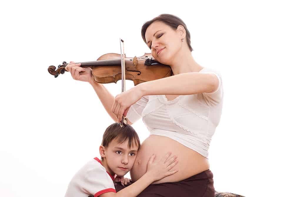 mother playing violin while child listens to baby in her stomach